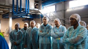 Grupo de trabalhadores terceirizados de jaleco e touca em uma unidade de processamento de alimentos (foto real, Pexels)