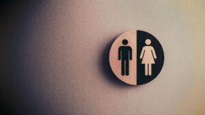 Placa redonda de banheiro masculino e feminino fixada em parede de ambiente de trabalho