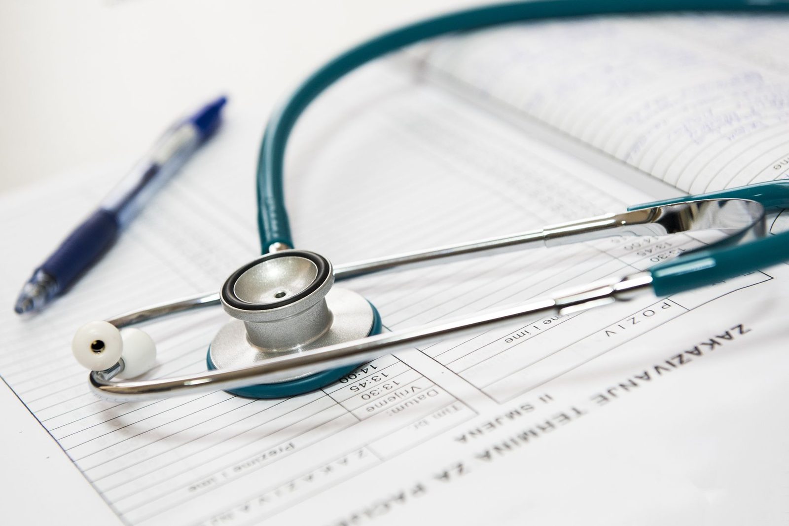Estetoscópio e caneta pousados sobre um formulário médico, sem pessoas, representando o exame do corpo deixado de lado quando a incapacidade é decidida só por análise de documentos