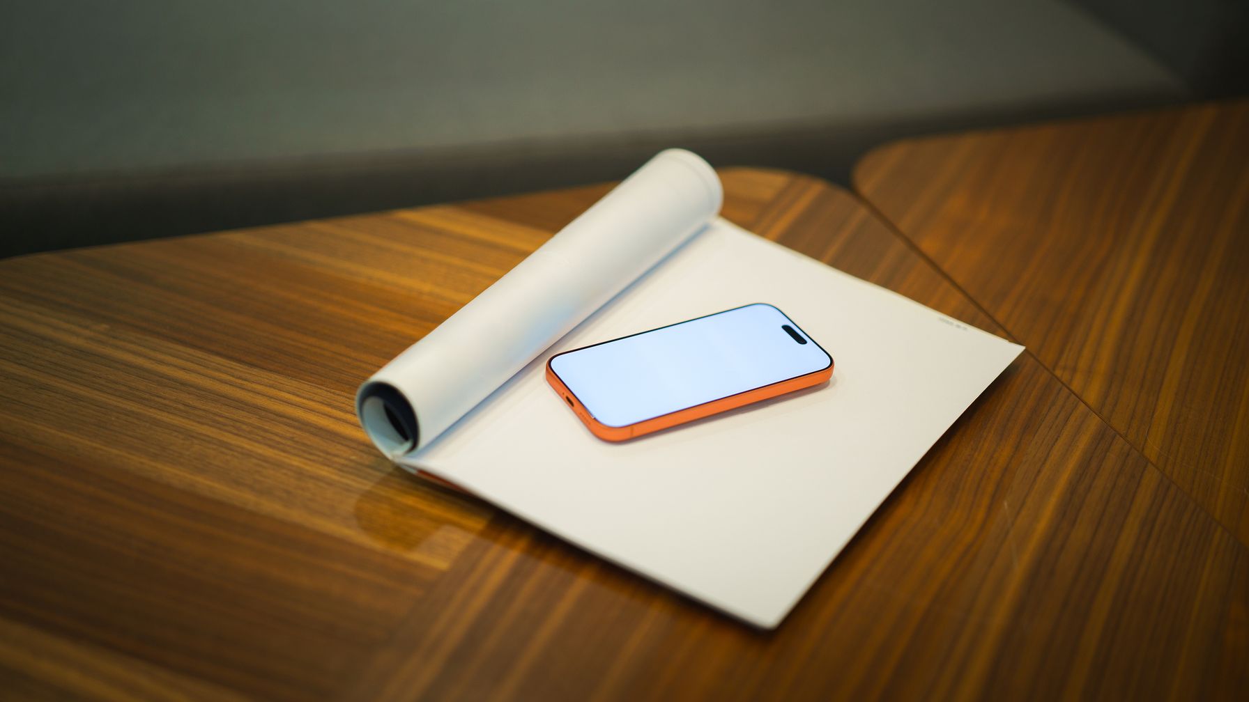Celular ao lado de documentos impressos sobre a mesa de escritório, ilustrando a consulta do extrato do CNIS no aplicativo Meu INSS e a comparação com os papéis do vínculo