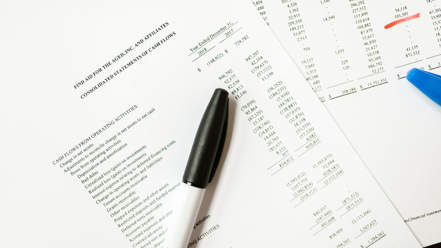 Calculadora e caneta sobre extratos impressos em uma mesa, ilustrando o cálculo por faixas do benefício menor na acumulação de pensão por morte com aposentadoria