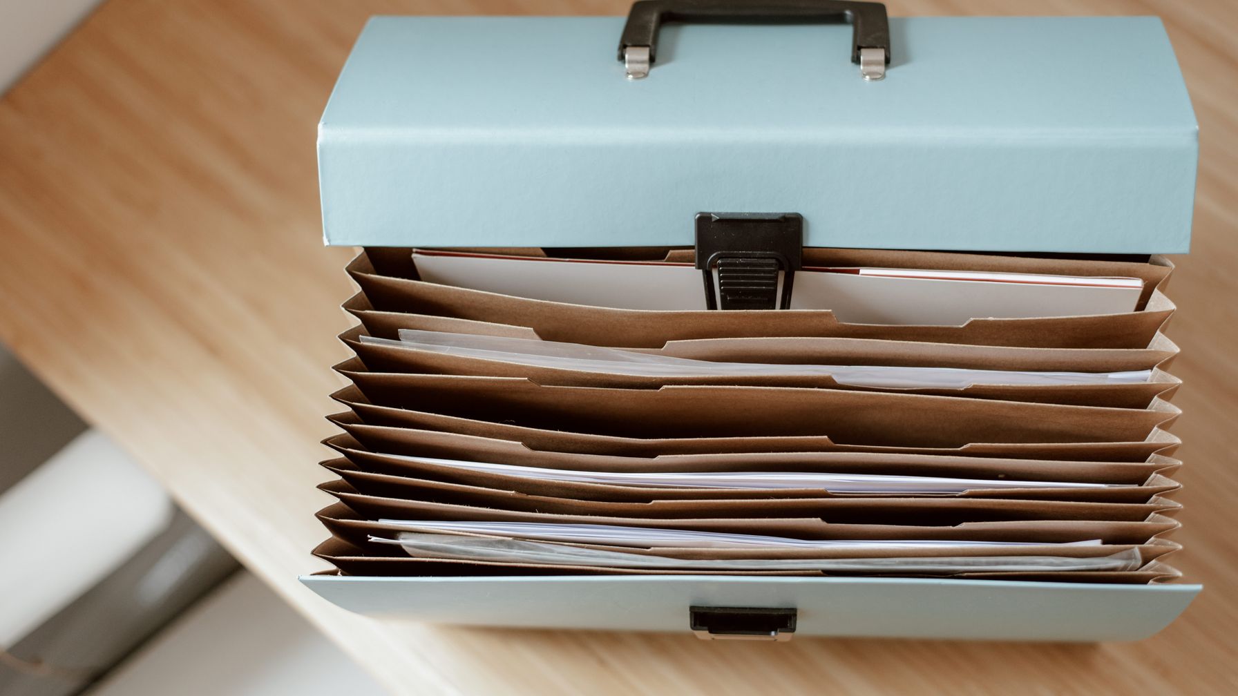 Pasta de documentos aberta com papéis impressos e óculos de leitura sobre a mesa, ilustrando a conferência conjunta das cartas de concessão, do extrato de pagamento e da memória de cálculo do INSS